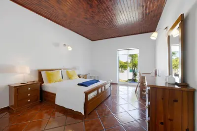 a bedroom with a bed and a chair in it at Villa Oliveira in Aljezur
