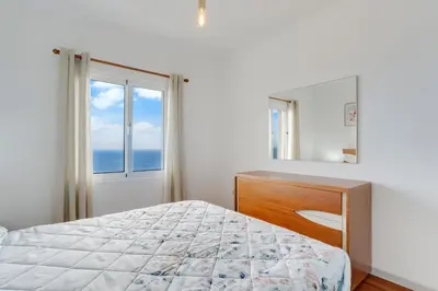 a bedroom with a bed and a large window at Santa Cruz Apartment with Sea View by Holiday Rental Madeira in Santa Cruz