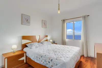 a bedroom with a bed and a large window at Santa Cruz Apartment with Sea View by Holiday Rental Madeira in Santa Cruz