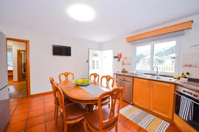 a kitchen with a wooden table and a dining room at Casa do Cantinho do Muro in São Vicente