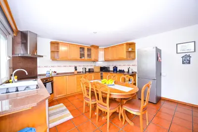 a kitchen with a table and chairs and a refrigerator at Casa do Cantinho do Muro in São Vicente