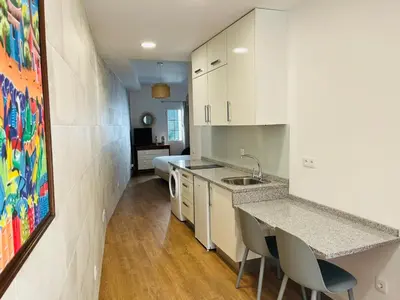 a kitchen with white cabinets and a table and chairs at Charming Funchal Studio II in Funchal