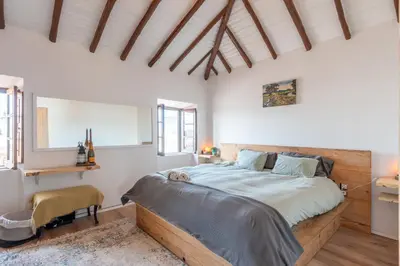 a bedroom with a large bed and a chair at Casa Carina Espiche in Espiche