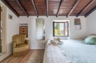 a bedroom with a large bed and a chair at Casa Carina Espiche in Espiche