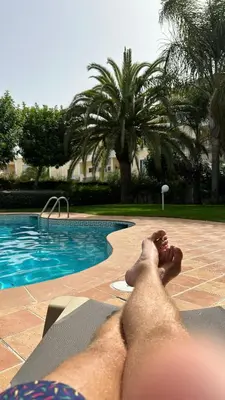 a man laying on a recliner next to a swimming pool at Amazing 2 Bedroom Apartment near beach with pool in Lagos
