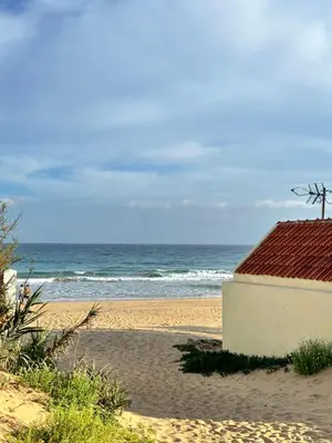 a building on the beach with the ocean in the background at Golden Beach House in Porto Santo