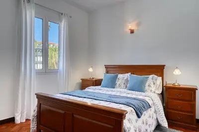 a bedroom with a bed with blue pillows and a window at Casa do Valentim, a Home in Madeira in Ponta do Sol