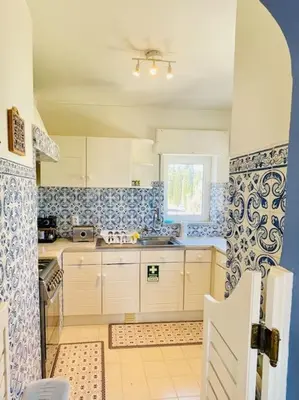 a kitchen with white cabinets and blue and white tiles at Avenue Q, Beach Apartment in Luz in Luz