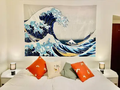 a bed with orange pillows and a painting of a wave at Avenue Q, Beach Apartment in Luz in Luz