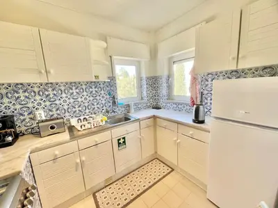 a kitchen with white cabinets and a white refrigerator at Avenue Q, Beach Apartment in Luz in Luz