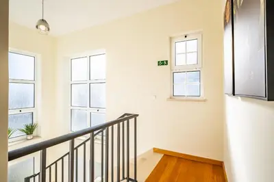 a staircase in a white room with windows at Gaula Residence by Homie in Santa Cruz