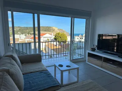 a living room with a couch and a tv and a balcony at Casa Sea Love Luz in Luz