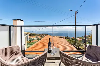 a table and chairs on a balcony with a bottle of wine at Panoramic Views I I in Caniço