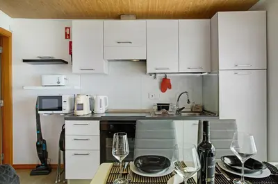 a kitchen with white cabinets and a table with wine glasses at Panoramic Views I in Caniço