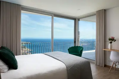 a bedroom with a bed and a view of the ocean at Peak A Boo Private Heated Pool and Private Parking in Câmara de Lobos