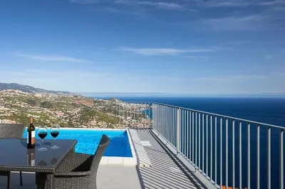 a balcony with a table with wine glasses on it at Peak A Boo Private Heated Pool and Private Parking in Câmara de Lobos