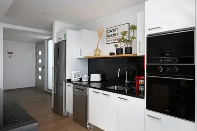 a kitchen with white cabinets and black appliances at Peak A Boo Private Heated Pool and Private Parking in Câmara de Lobos