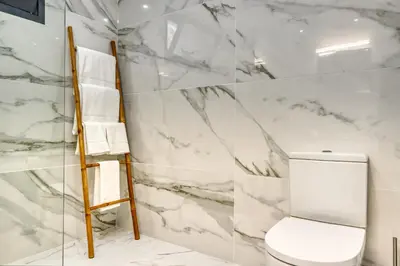 a white marble bathroom with a toilet and a ladder at Tristão Vaz II, a Home in Madeira in Machico