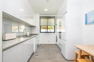 a kitchen with white cabinets and a wooden table at Apartment with ocean view and parking in Funchal