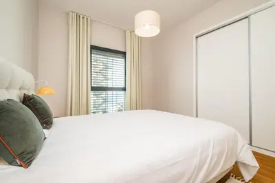 a white bedroom with a large bed and a window at Apartment with ocean view and parking in Funchal