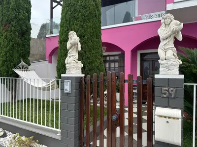 a fence with two statues in front of a pink house at Residência Mendonça in Faial