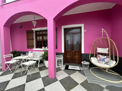 a pink house with chairs and a table in front of it at Residência Mendonça in Faial