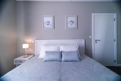 a white bedroom with a bed with two pillows at Blue House in Ponta do Sol