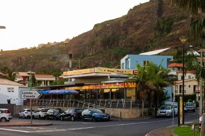a parking lot with cars parked in front of a building at Blue House in Ponta do Sol