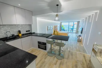 a kitchen with white cabinets and a black counter top at Sea Breeze III in Caniço