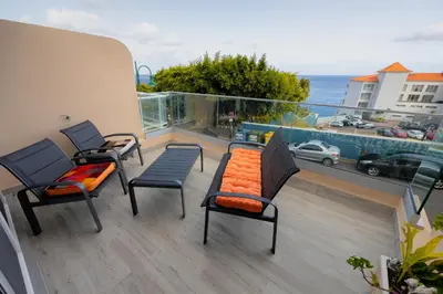 a balcony with three chairs and a bench on a balcony at Sea Breeze III in Caniço