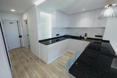 a kitchen with white cabinets and a black counter top at Sea Breeze III in Caniço