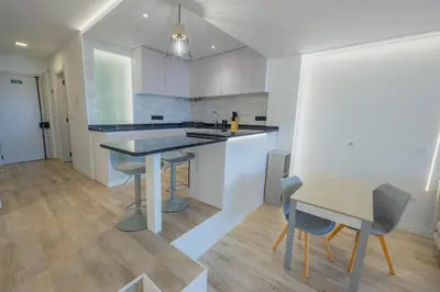 a kitchen with white cabinets and a table with chairs at Sea Breeze III in Caniço