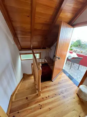 a staircase in a house with a wooden ceiling at Waves Song - Cottage in Porto Moniz