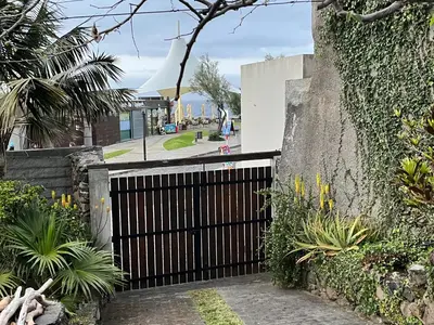 a black gate in a stone wall with plants at Waves Song - Cottage in Porto Moniz