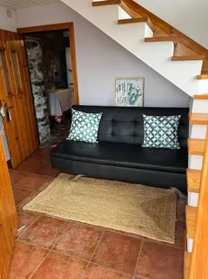 a black couch sitting in a living room at Waves Song - Cottage in Porto Moniz