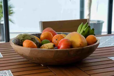 a wooden bowl of fruit sitting on a table at GuestReady - Hillside Oceanview Heaven in Funchal