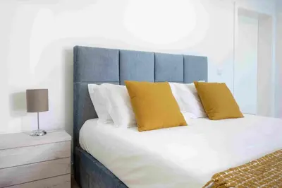 a bed with a blue headboard and two yellow pillows at GuestReady - Hillside Oceanview Heaven in Funchal