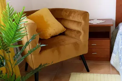 a brown chair with a yellow pillow next to a table at Entire flat 70sq m at Luz just 400m beach distance in Luz