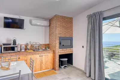 a kitchen with a fireplace and a tv and a window at Studio 92, a Home in Madeira in Ponta do Sol