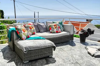 a wicker couch sitting on a patio with the ocean at Studio 92, a Home in Madeira in Ponta do Sol