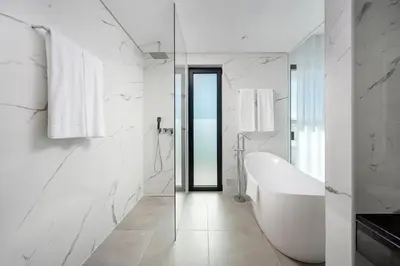 a white bathroom with a tub and a glass door at Vila Luna B&B in Lagos