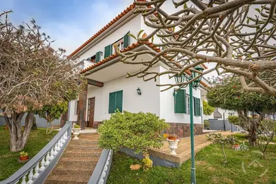 a white house with green shutters and trees at Garden House in Funchal