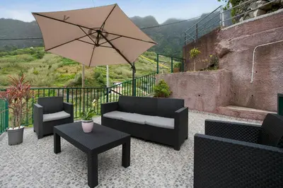 a patio with couches and a table and an umbrella at São Vicente House in São Vicente