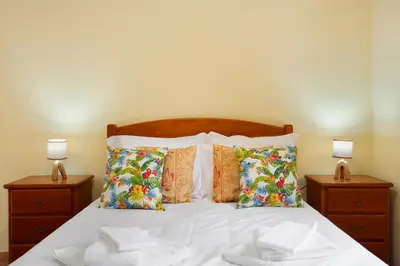 a bed with white sheets and pillows and two lamps at São Vicente House in São Vicente