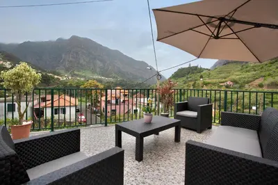 a patio with a table and chairs and an umbrella at São Vicente House in São Vicente
