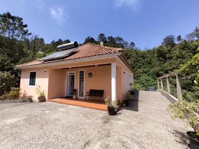 a small house with a bench on a driveway at Casa Rosa - Vereda da Ilha in Santana