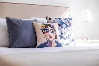 a bed with pillows and a painting of a woman at Apartamentos Progresso 1º Esq in Funchal