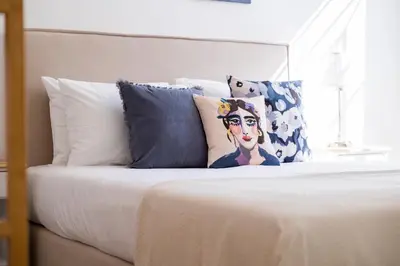 a bed with white sheets and pillows on it at Apartamentos Progresso 1º Esq in Funchal