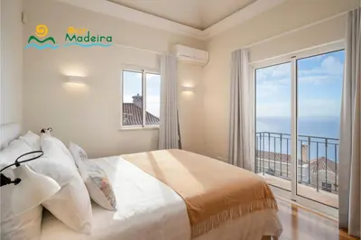 a bedroom with a bed and a large window at OurMadeira - Palheiro Ocean in Funchal