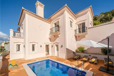a villa with a swimming pool in front of a house at OurMadeira - Palheiro Ocean in Funchal